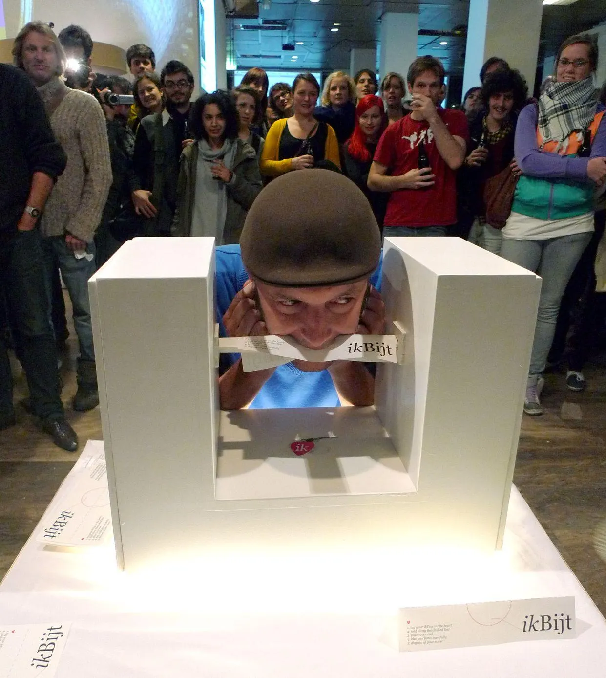 A crowd gathered around a lit white kiosk