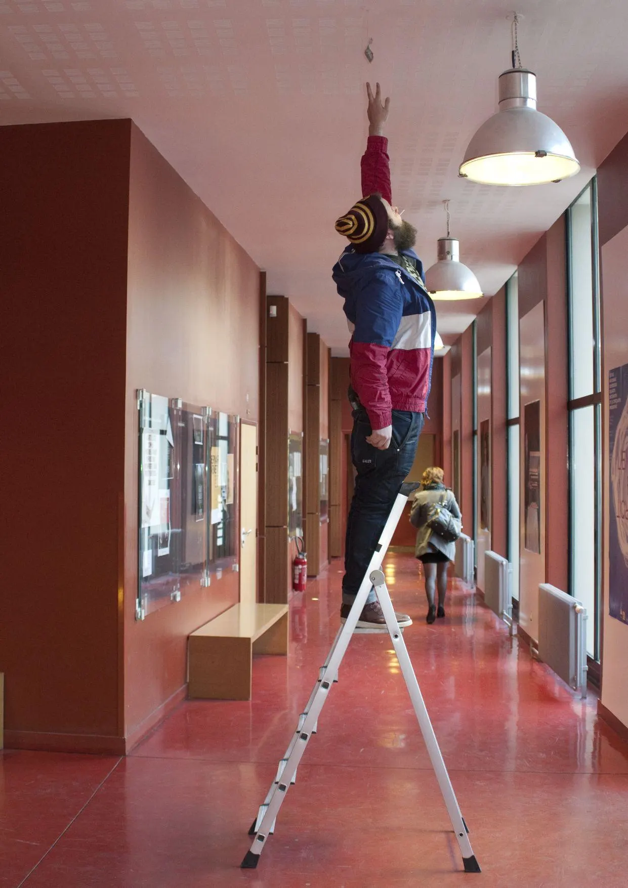 Corridor with a person on a stepladder and a hanging lamp