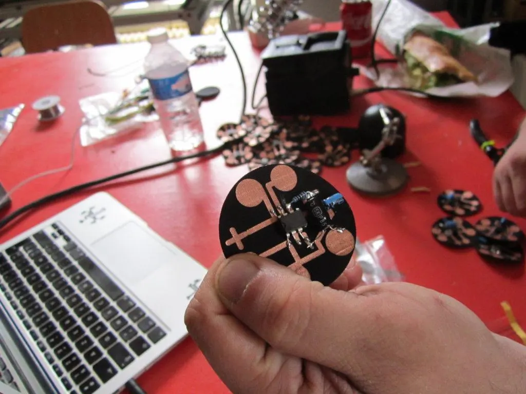 Hands soldering electronic components on a red table