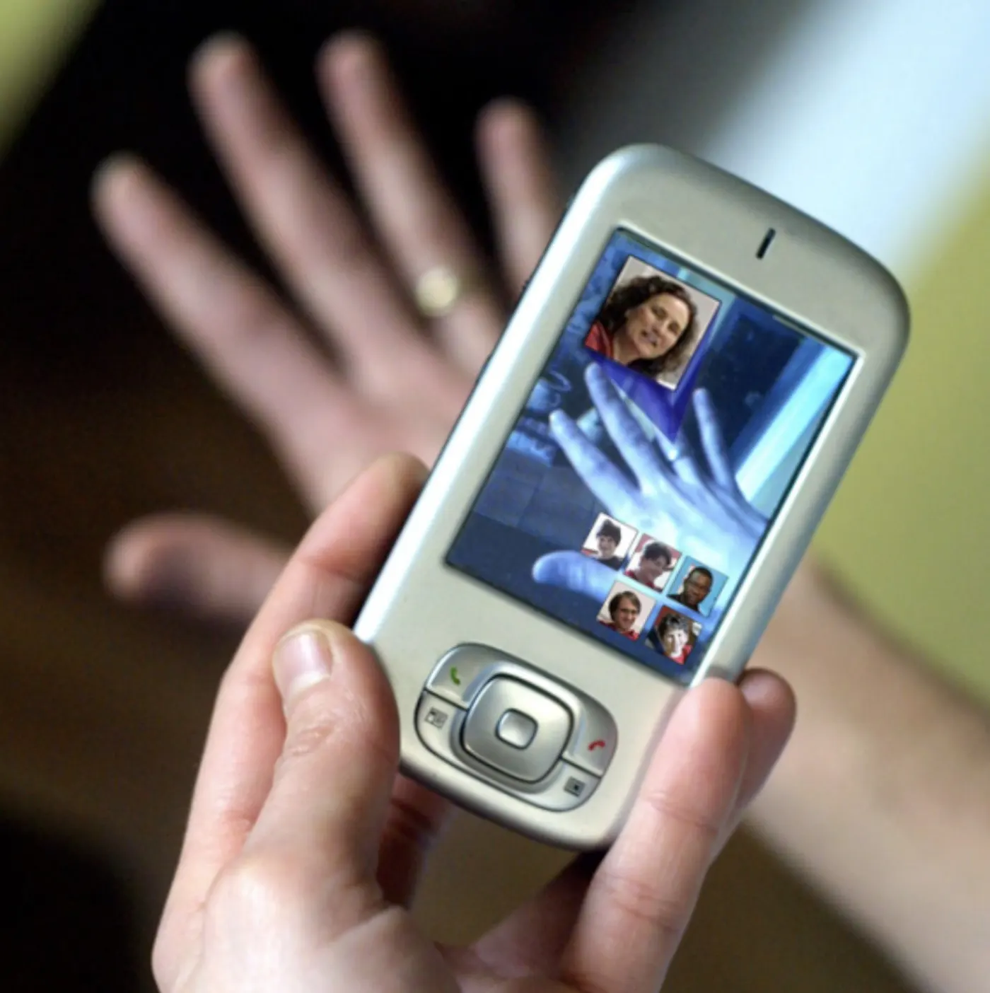 A hand holding a phone displaying photographs, next to strung beads